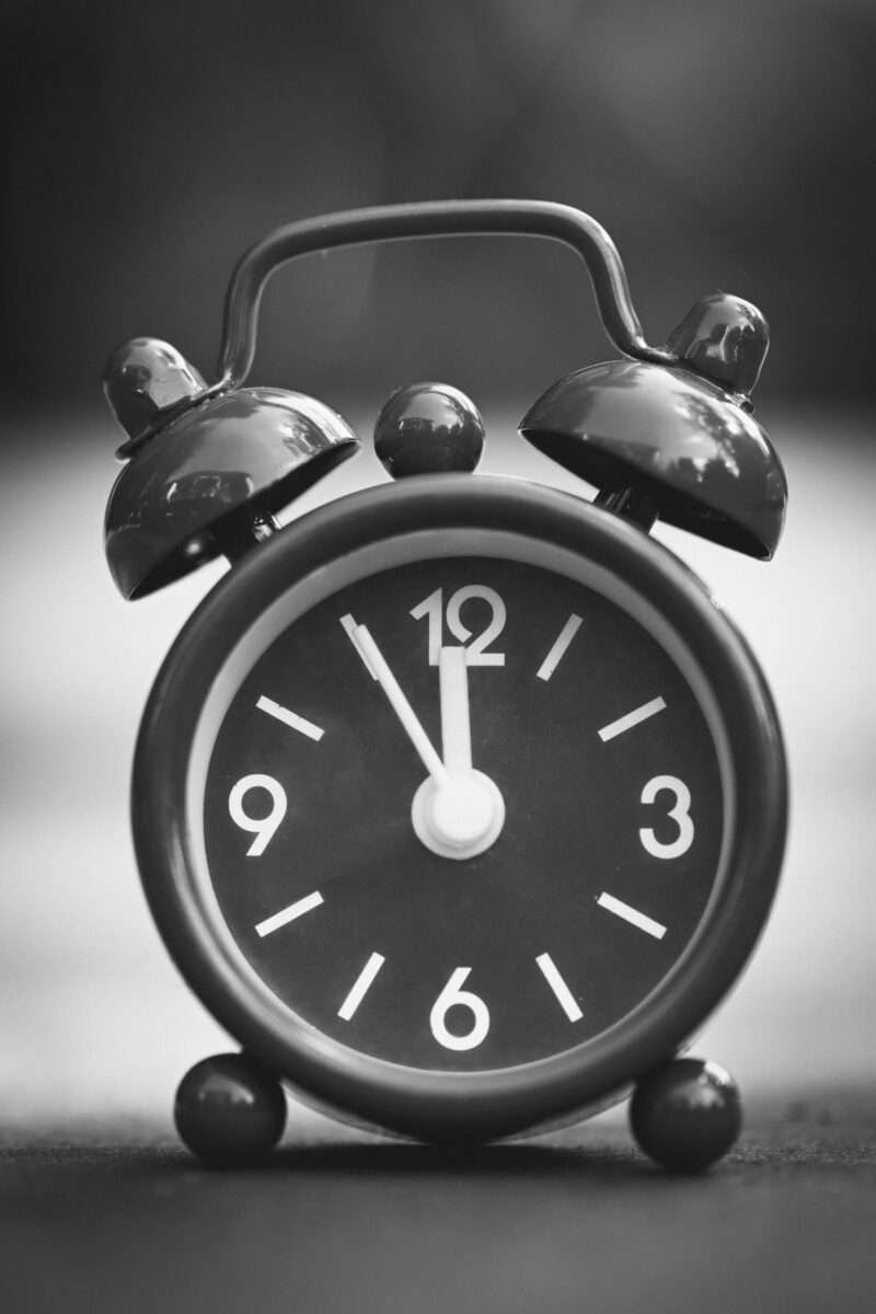 Close-up of a classic vintage alarm clock showing 12 o'clock in black and white.